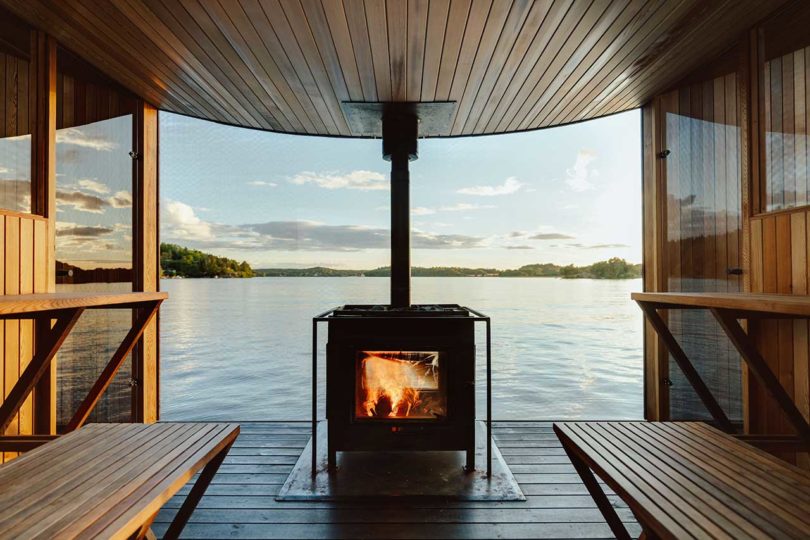interior of modern wooden floating sauna on water with fire burning
