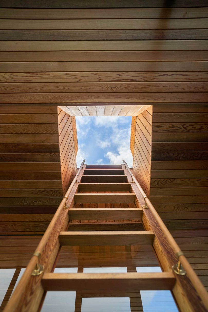 looking up ladder to roof of modern wooden floating sauna on water