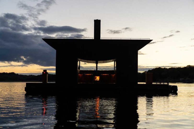 twilight view of modern wooden floating sauna on water