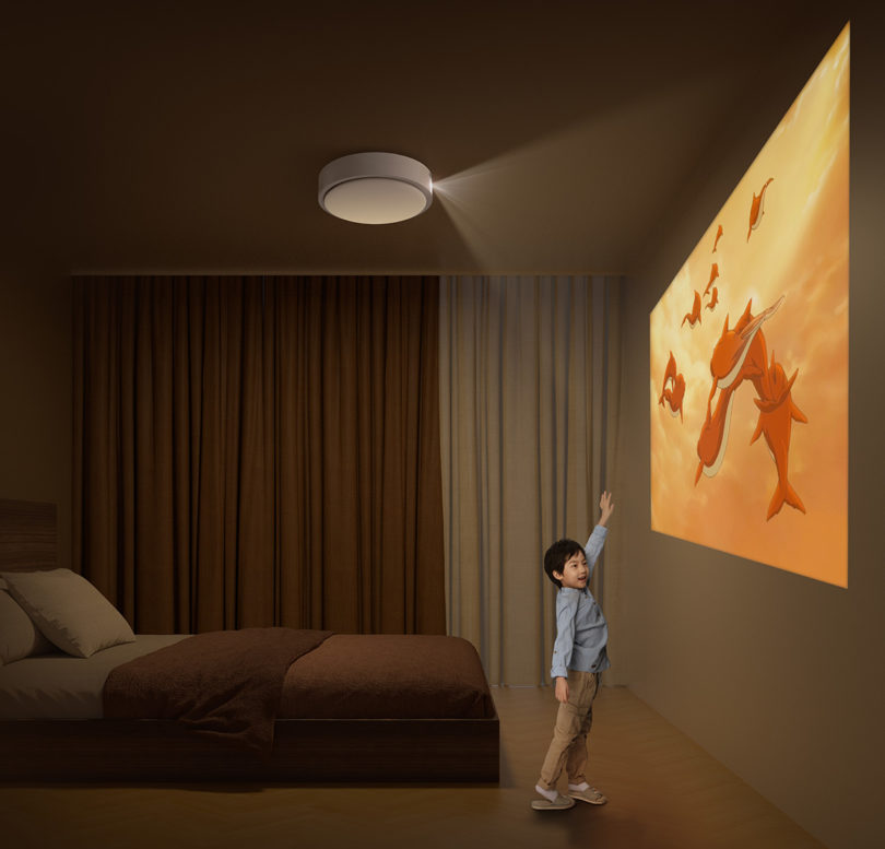 Small asian boy standing near projected picture illustrating maximum 100" projected picture on wall.