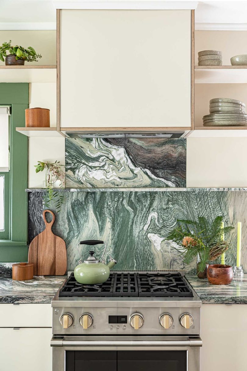 framed view of modern kitchen with stainless stove and green and white marble