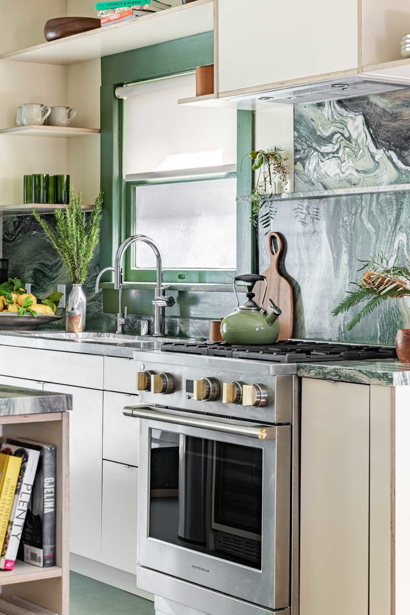 نمای قاب شده آشپزخانه مدرن با اجاق گاز ضد زنگ و سنگ مرمر سبز و سفید