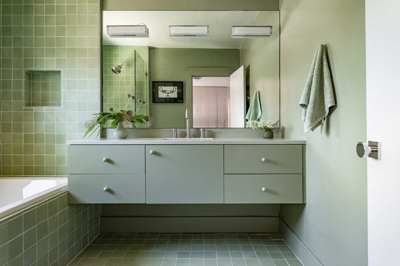 modern bathroom with muted green cabinet and matching tile