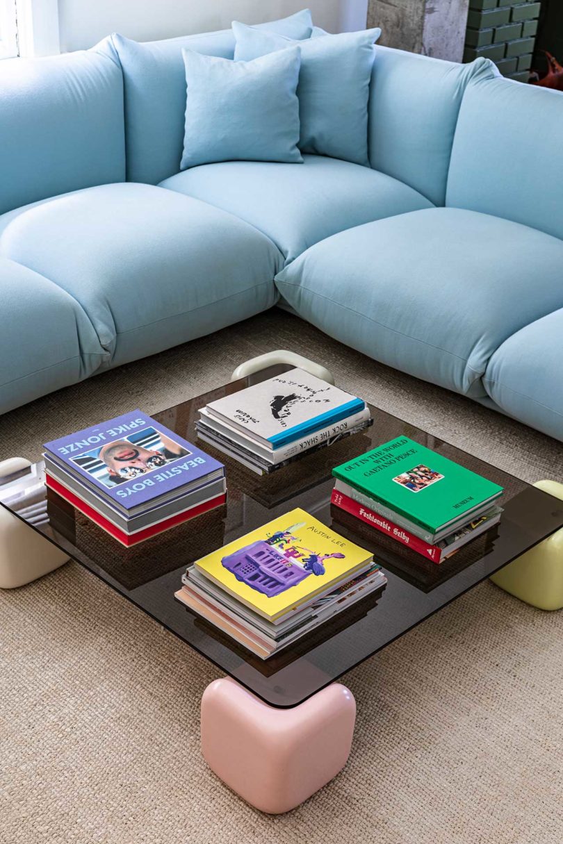 modern living room with light blue section sofa and coffee table with books stacked