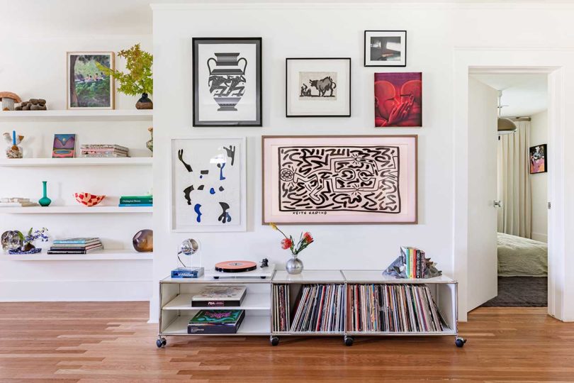 gallery wall full of art with low console with record player and vinyl