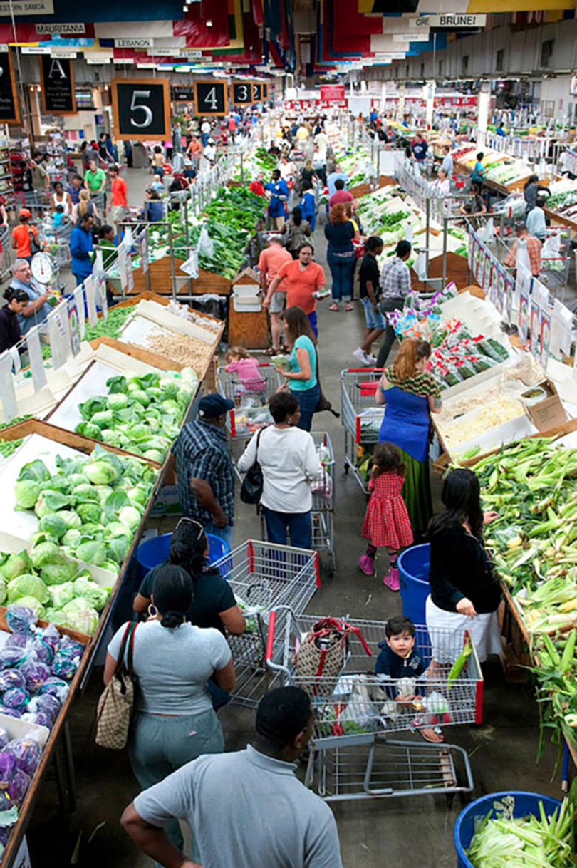 high angle view of shoppers making their way down a wide aisle with vegetables displayed on both sides