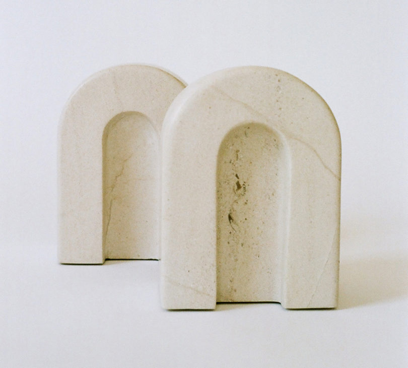 two light marble bookends shaped like arches