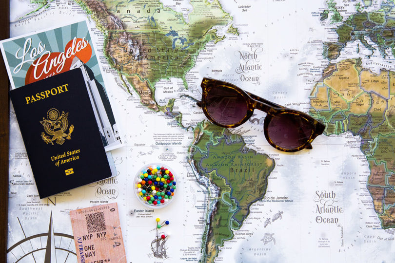 flat lay of world map, sunglasses, and a passport