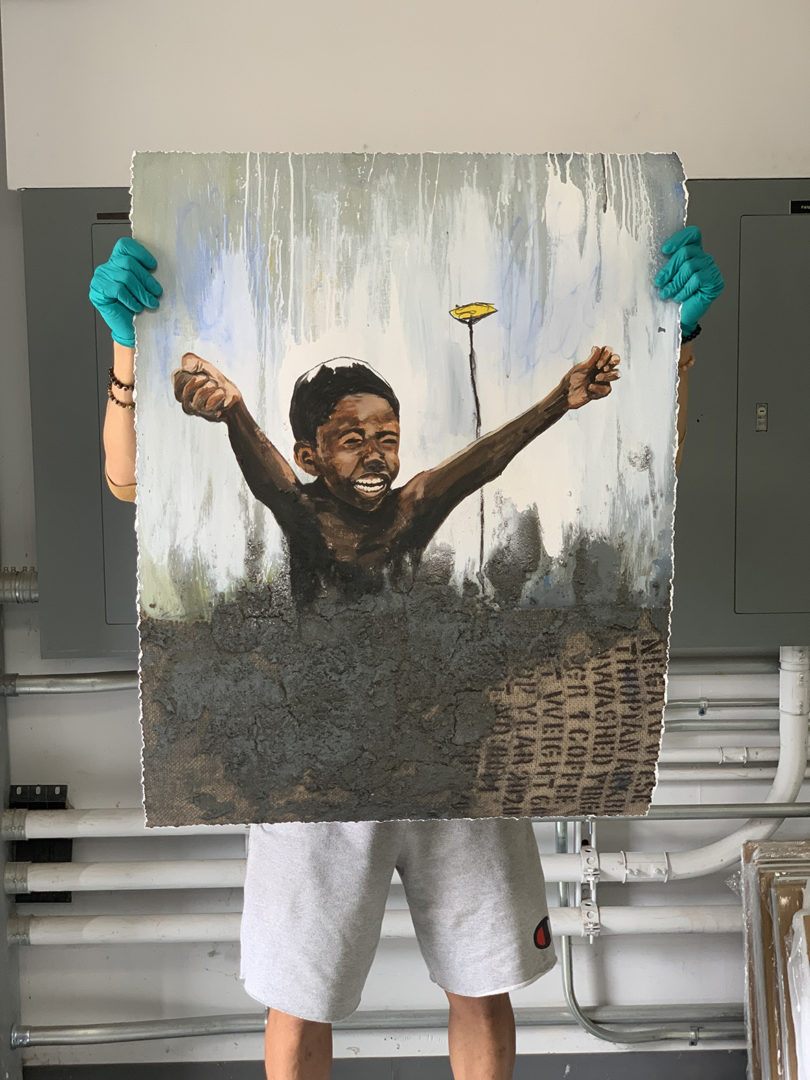 person holding up a painting of a child with their arms raised up in the air