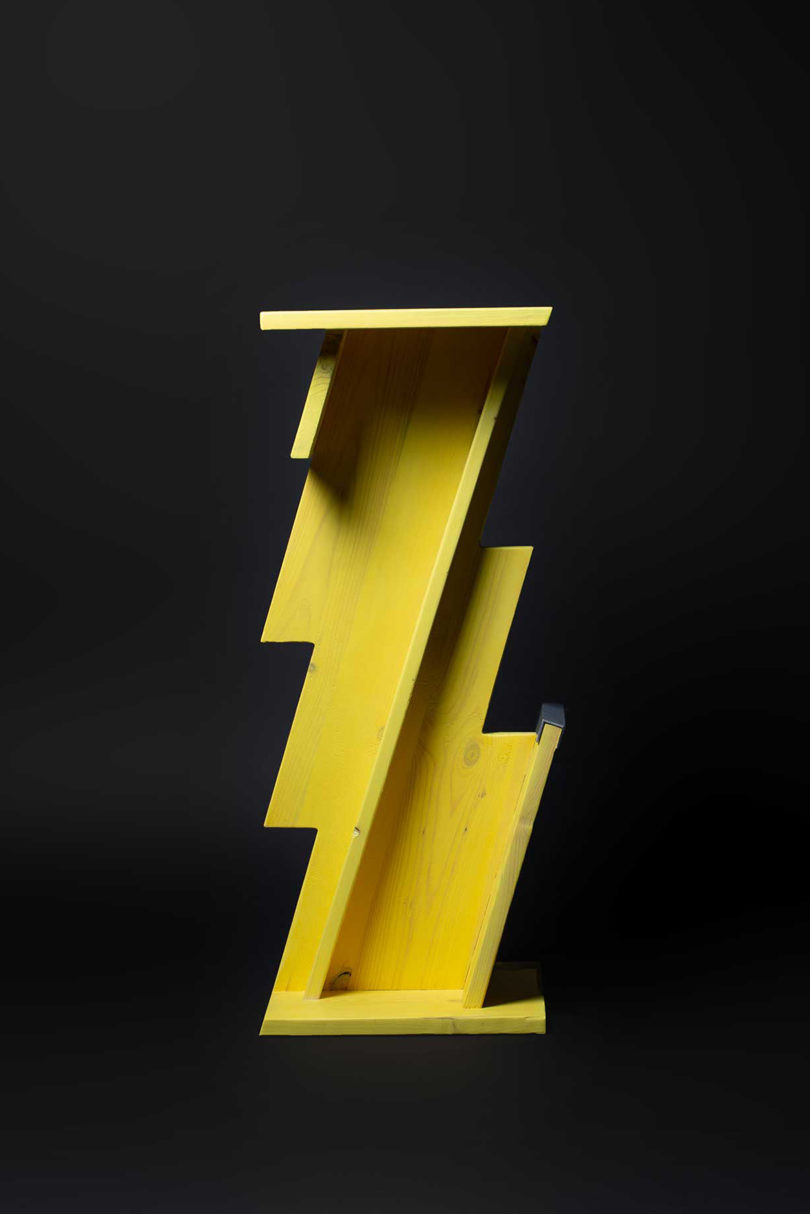 tall yellow lightning bolt shaped table on black background