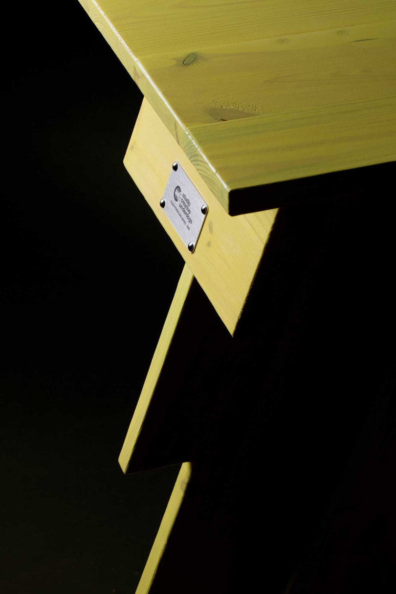 detail of tall yellow lightning bolt shaped table on black background