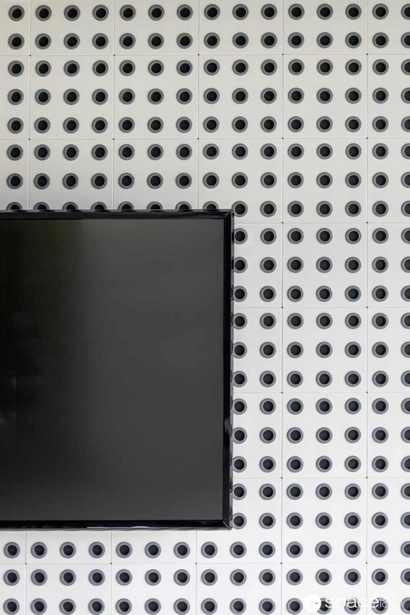 half view of TV mounted on the wall with perforated coasters on the wall