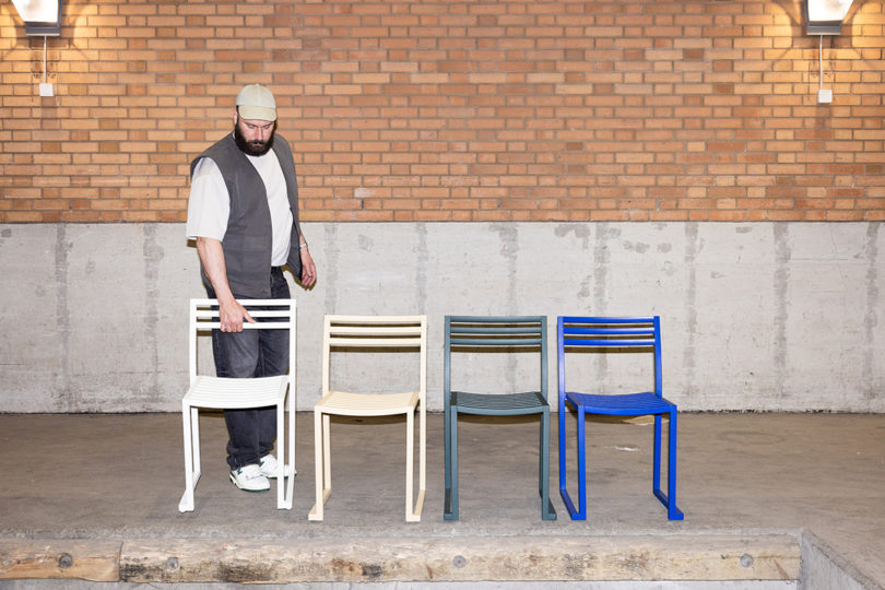 light-skinned man walking behind white, beige, graphite, and electric outdoor chairs lined up in a row