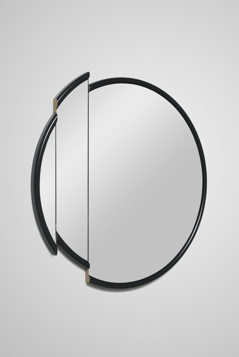 large round mirror with a black frame and slice taken out of it