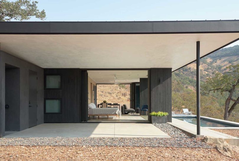 side view of small black modern home open to outdoors