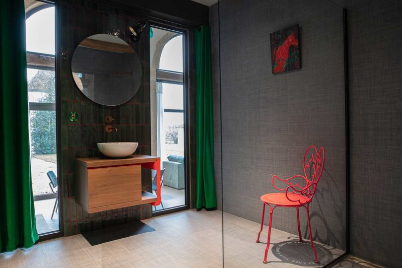 corner view of dark modern bathroom with red chair and accents