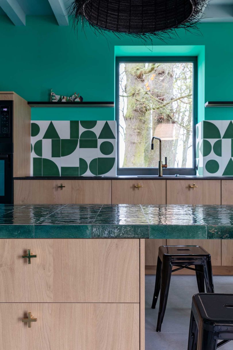 آشپزخانه مدرن بازسازی شده با کابینت های چوبی و دیوارهای فیروزه ای با کاشی هندسی