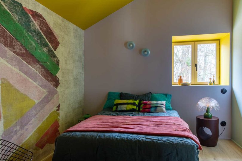 simple modern bedroom with patterned bedding and colorful mural