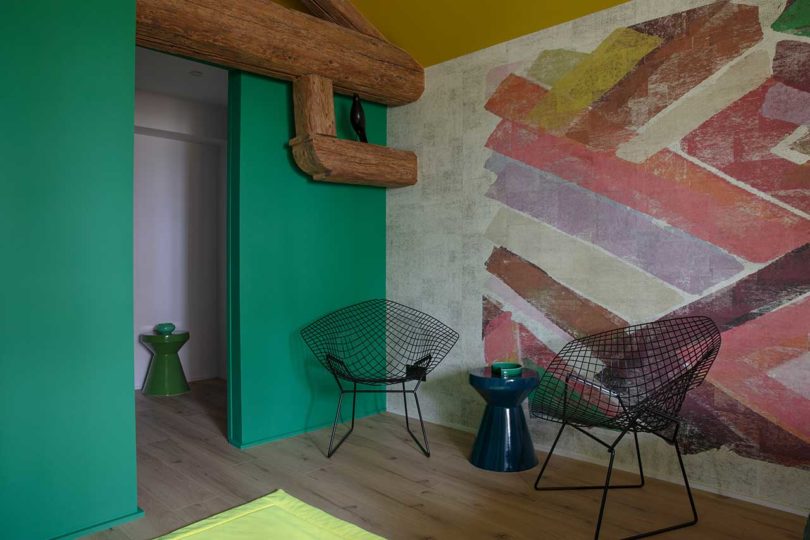 corner of modern bedroom with black wire chair and colorful mural on wall
