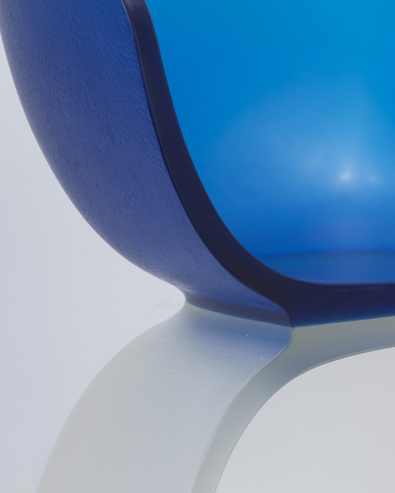 detail of blue and white glass chair with symmetrical seat and base on white background