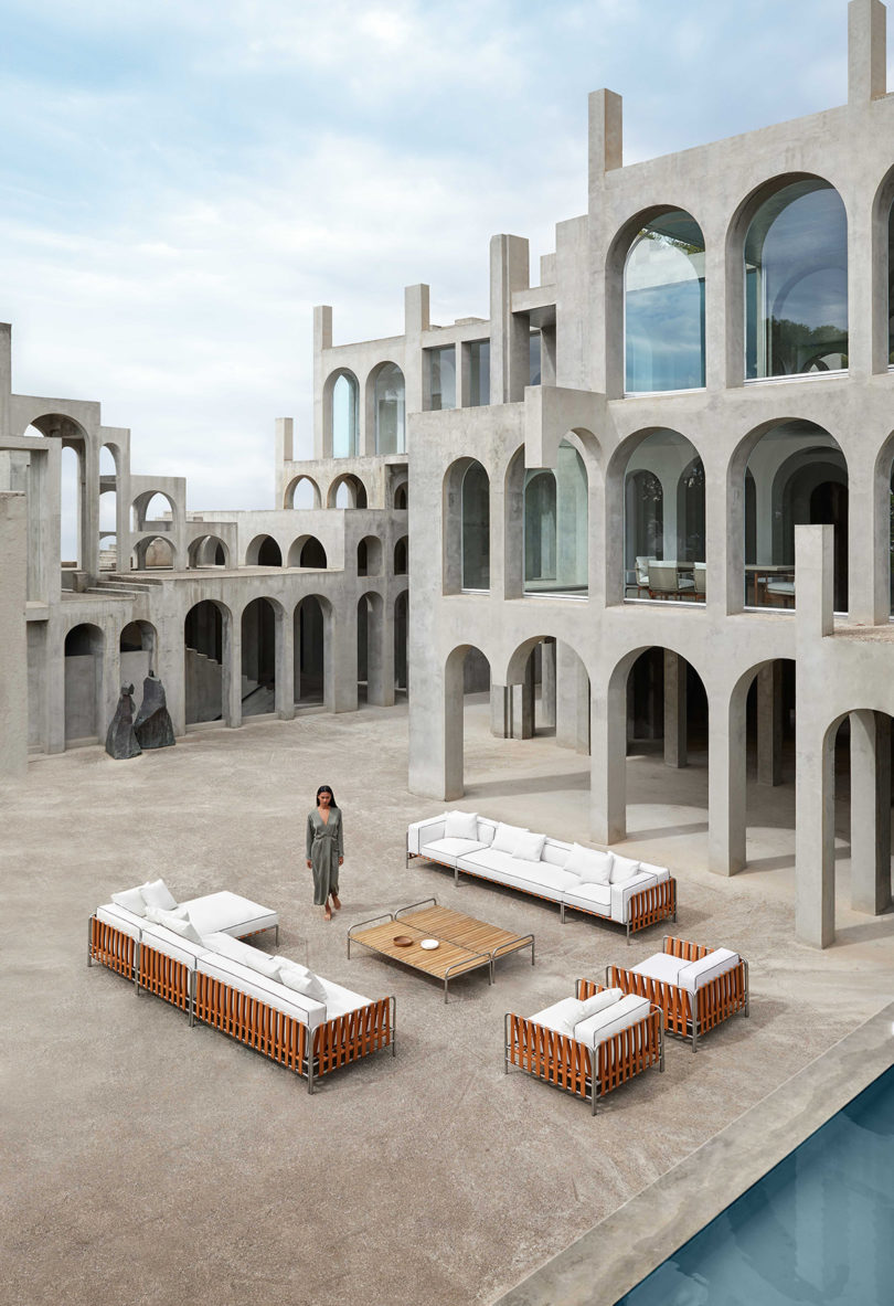 outdoor furniture collection with white upholstery arranged in an open space surrounded by tan buildings with lots of arches