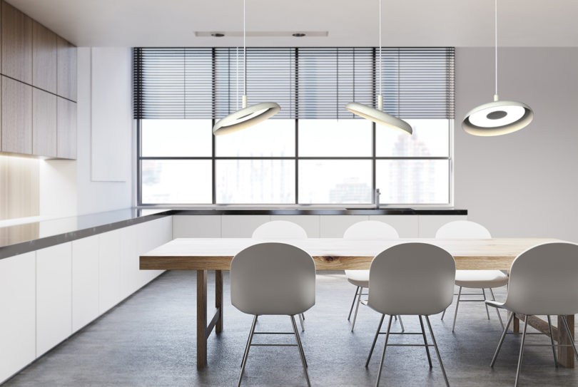 three white disc-shaped pendant lights hanging over a conference table
