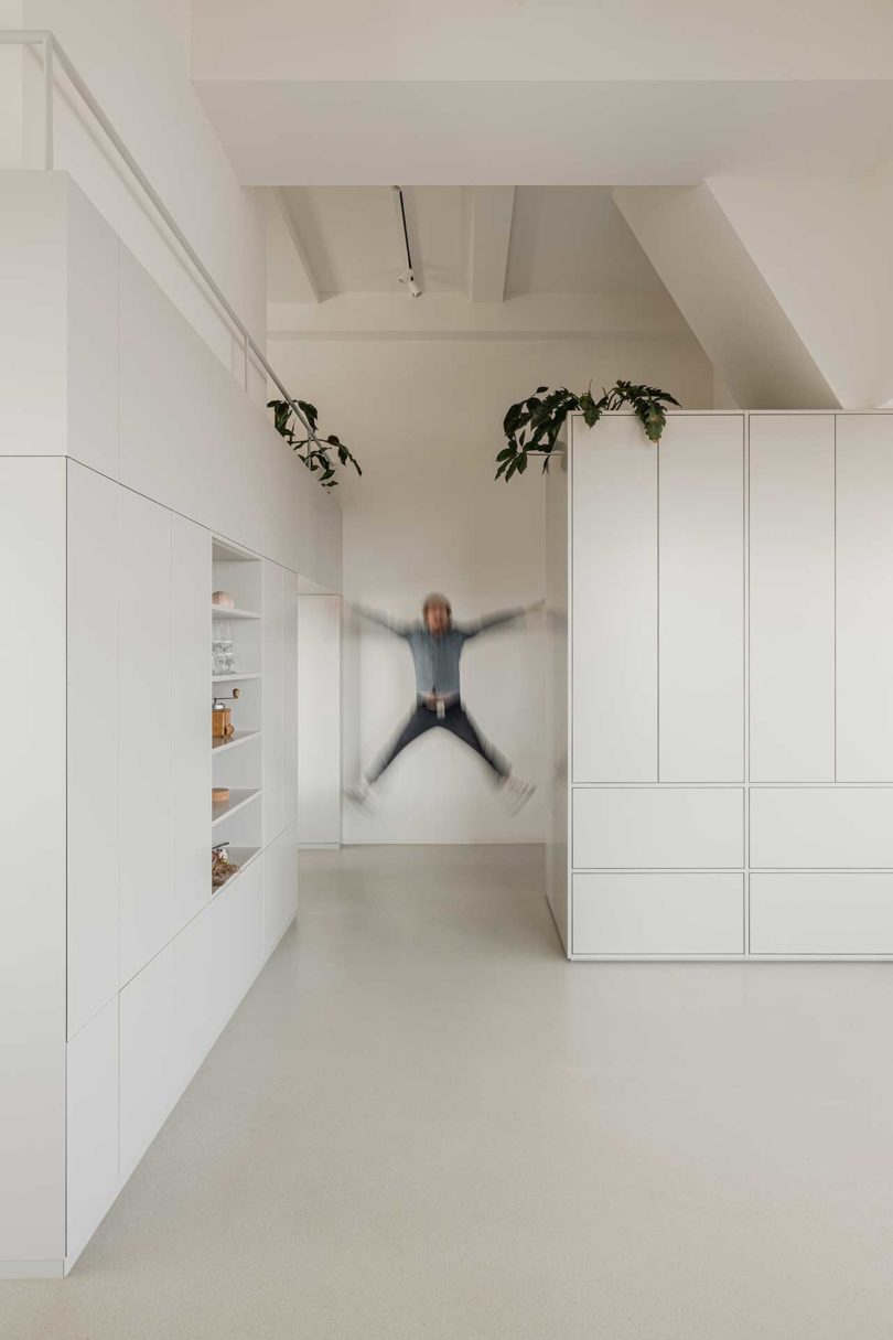 man jumping in white hallway of modern apartment