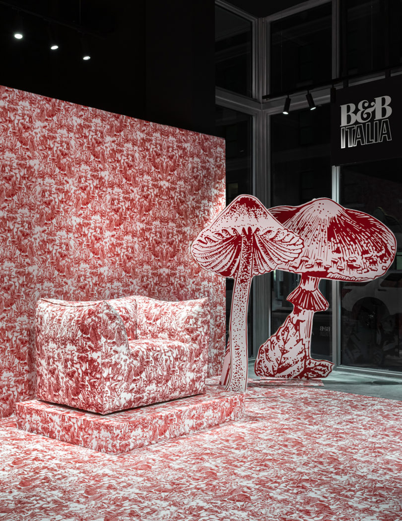 detail of dark red and white mushroom toile upholstered armchair on display in space covered with the pattern