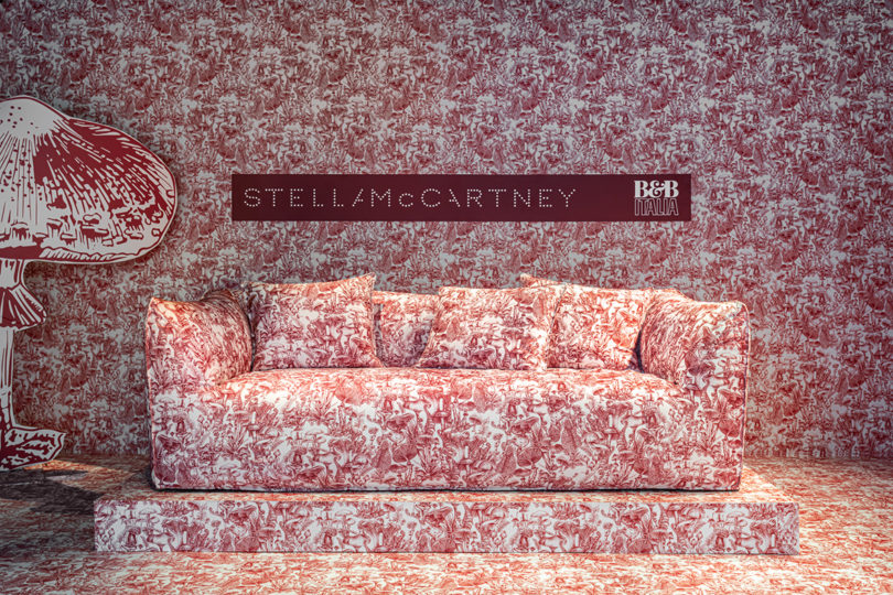 detail of dark red and white mushroom toile upholstered sofa on display in space covered with the pattern