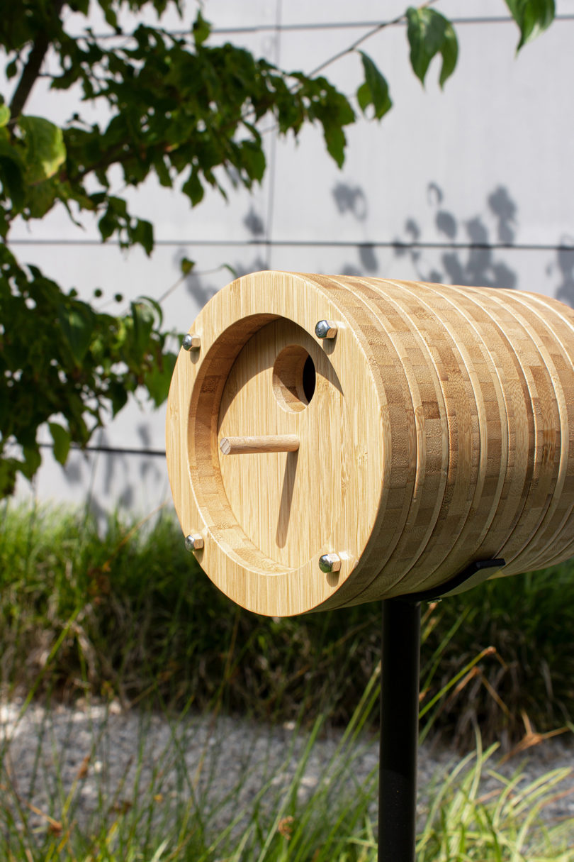 cylindrical bamboo birdhouse mounted on a metal stand