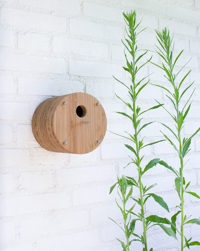 cylindrical bamboo birdhouse mounted on an outer wall