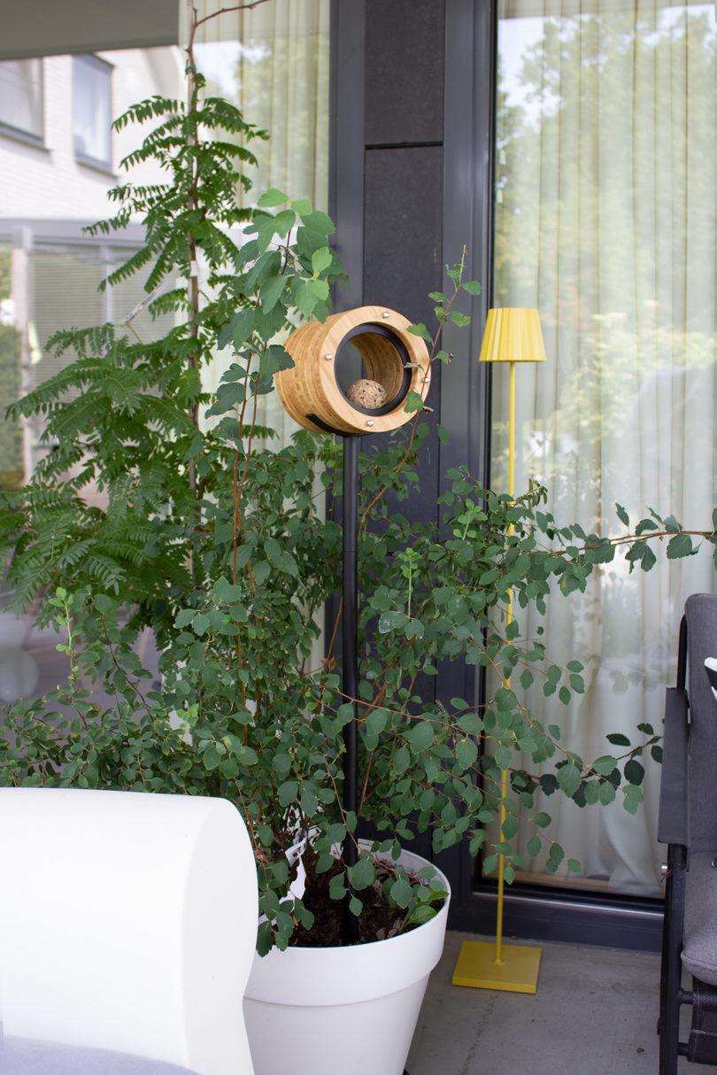 cylindrical bamboo bird feeder mounted on a metal stand