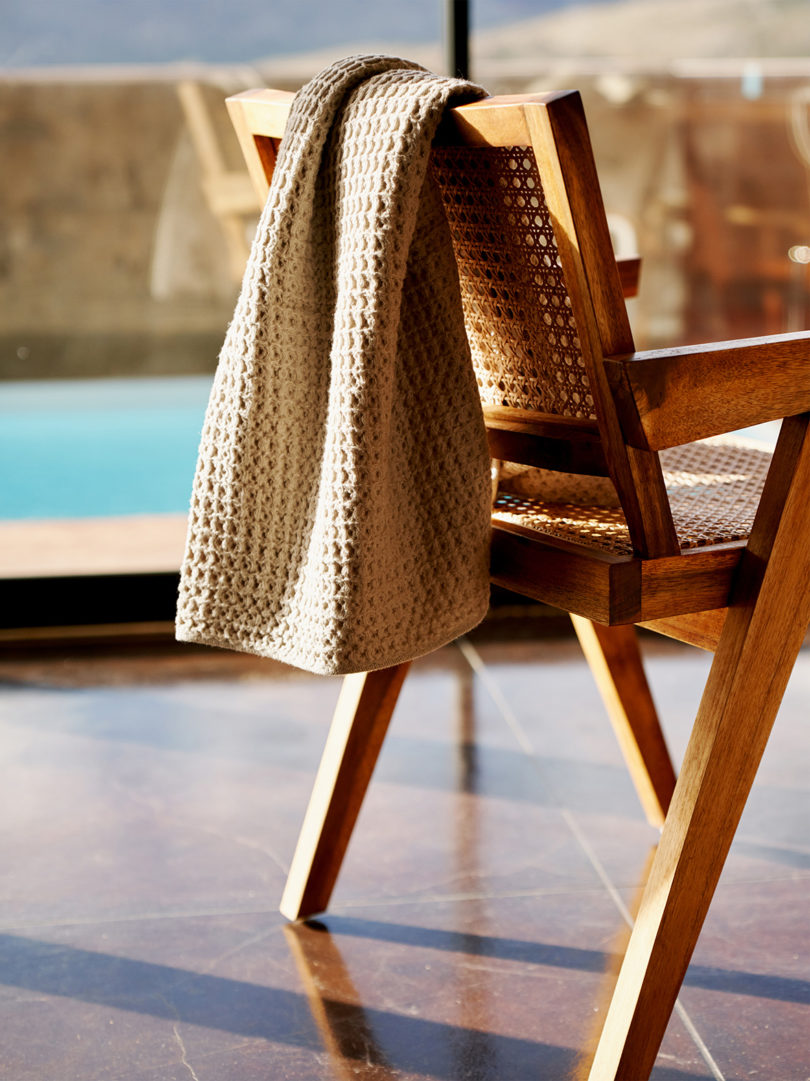 beige colored waffle weave bath towel tossed over the back of a wooden armchair