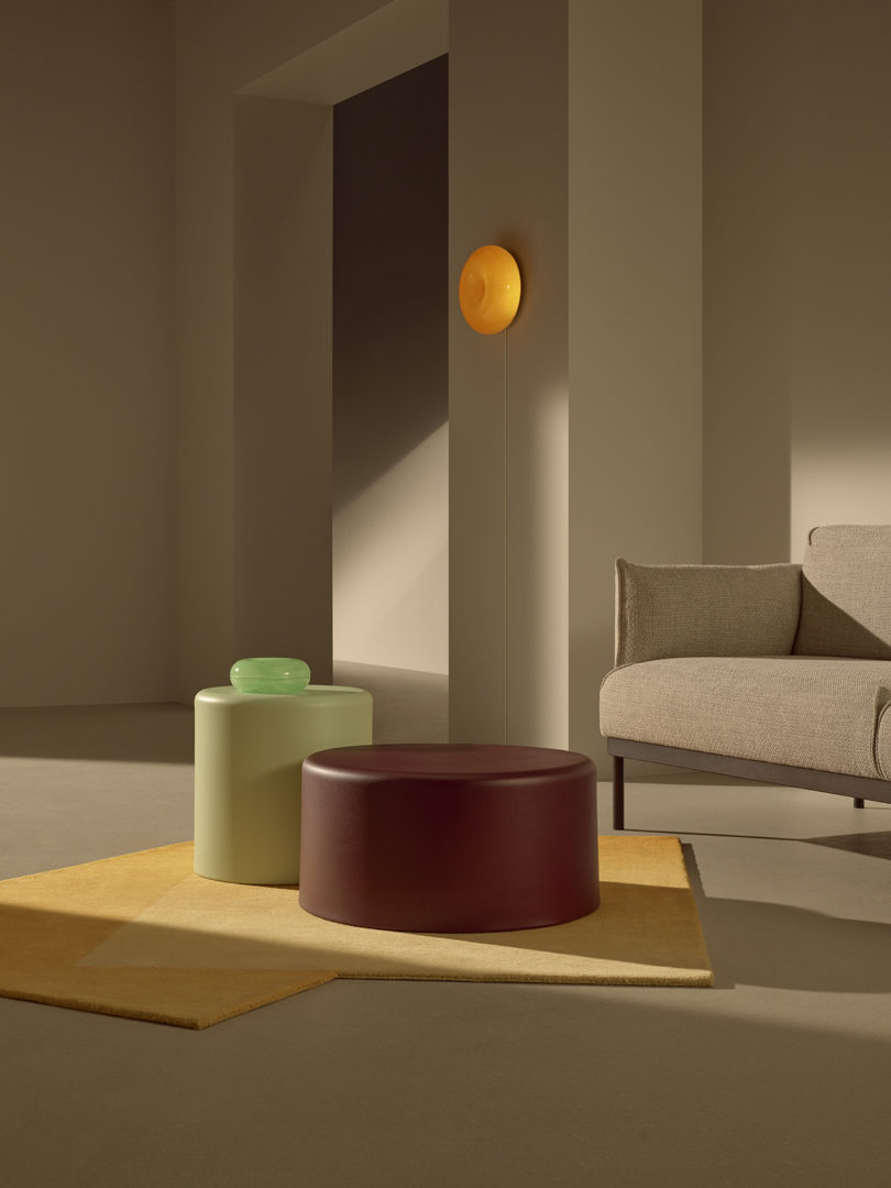 styled interior space with sofa, two coffee tables, a donut-shaped wall sconce, and donut-shaped table object