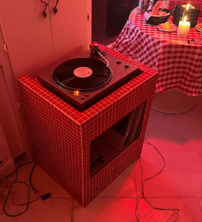Amore Mio Red Vinyl Stand staged next to red checkered candlelit dinner table with record ready to play.