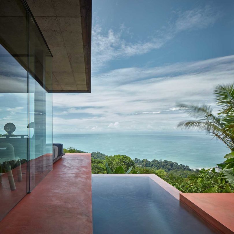 modern villa with red floors looking out to tropical landscape