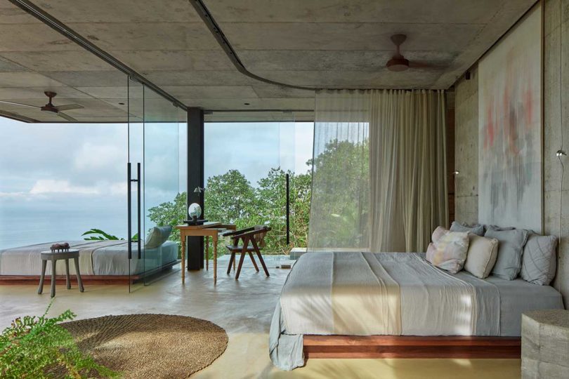 side view of modern bedroom looking out through floor to ceiling windows to green hillside