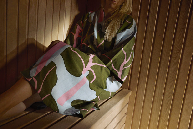 woman in a leaf patterned rob sits in a sauna