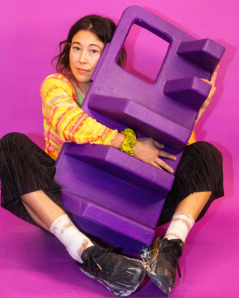 Designer Bailey Hikawa hugging a humanscale iPhone case in purple.