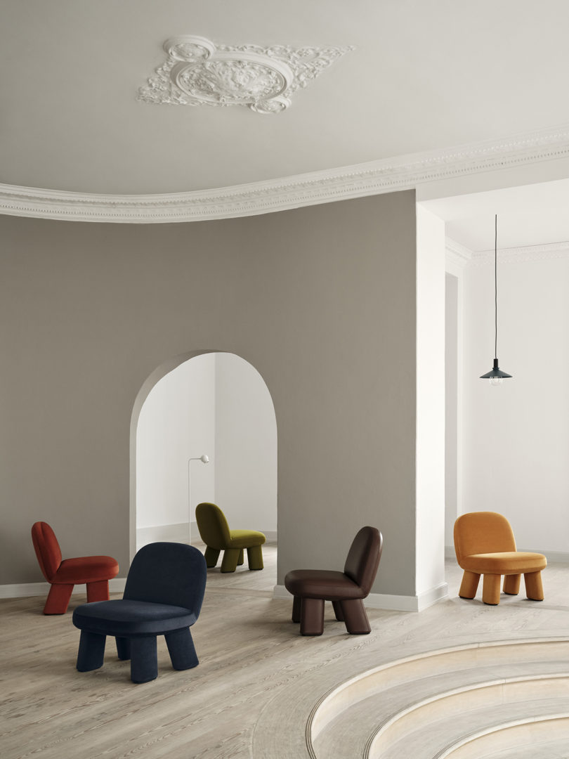 five colorful modern chairs scattered around an interior space