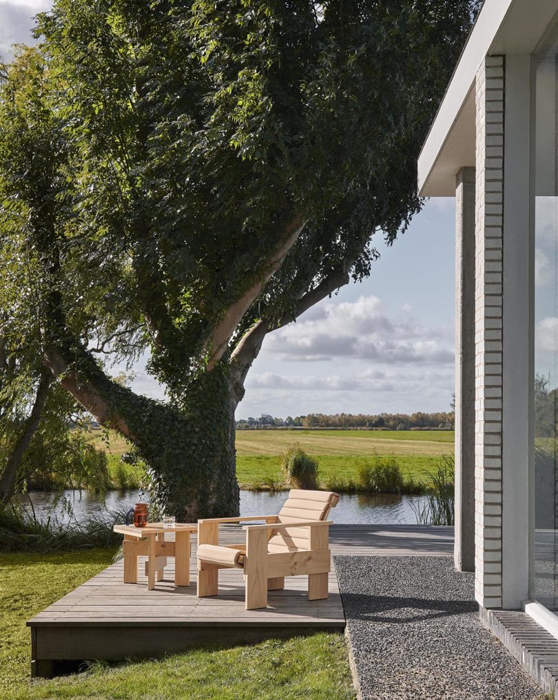 outdoor wood armchair and a side table sit outside in front of an open field