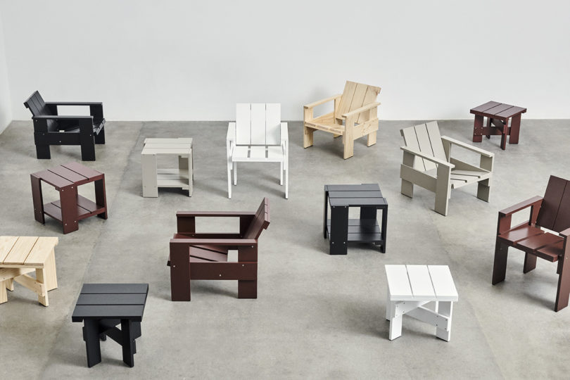 various colors of wooden outdoor armchairs and side tables arranged in an empty studio space