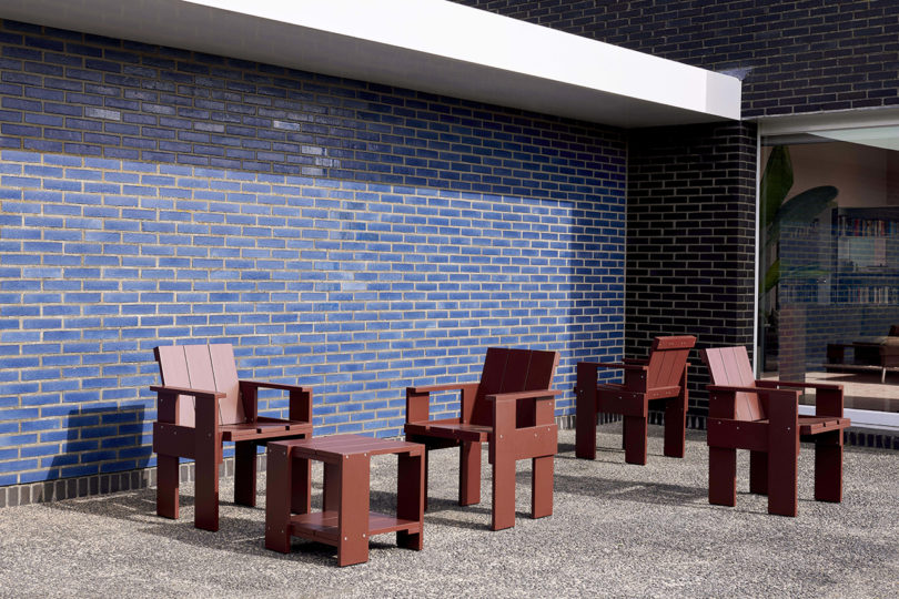rust colored outdoor chairs and side table in front of blue tiled wall