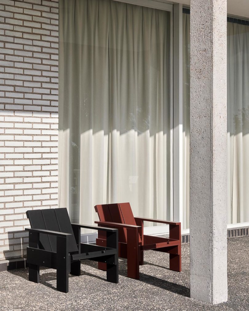 two outdoor armchairs sit outside in front of a white brick wall