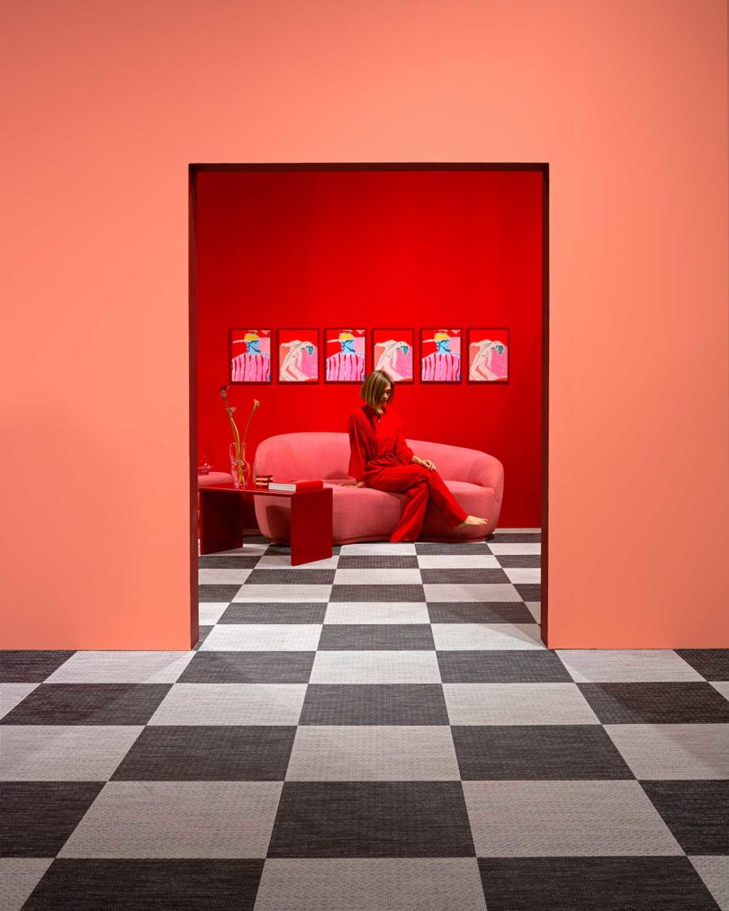 bold color-blocked exhibition looking into red living space with woman sitting on sofa