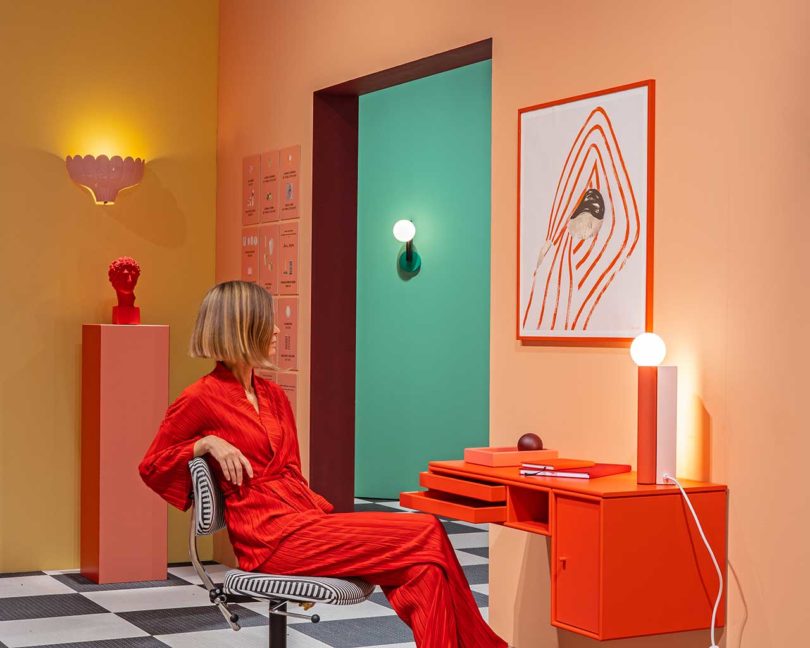 bold color-blocked exhibition office with woman in red sitting at desk