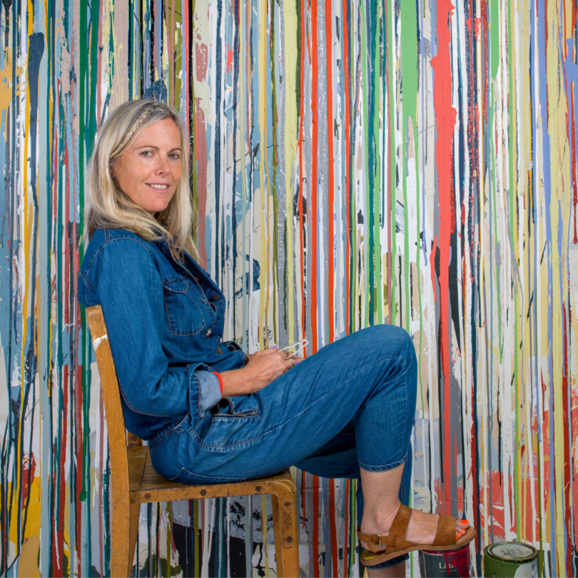 artist Ella Doran sitting in chair in front of striped painting