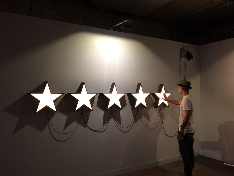 art installation of five illuminated stars in a line, a person interacts with them