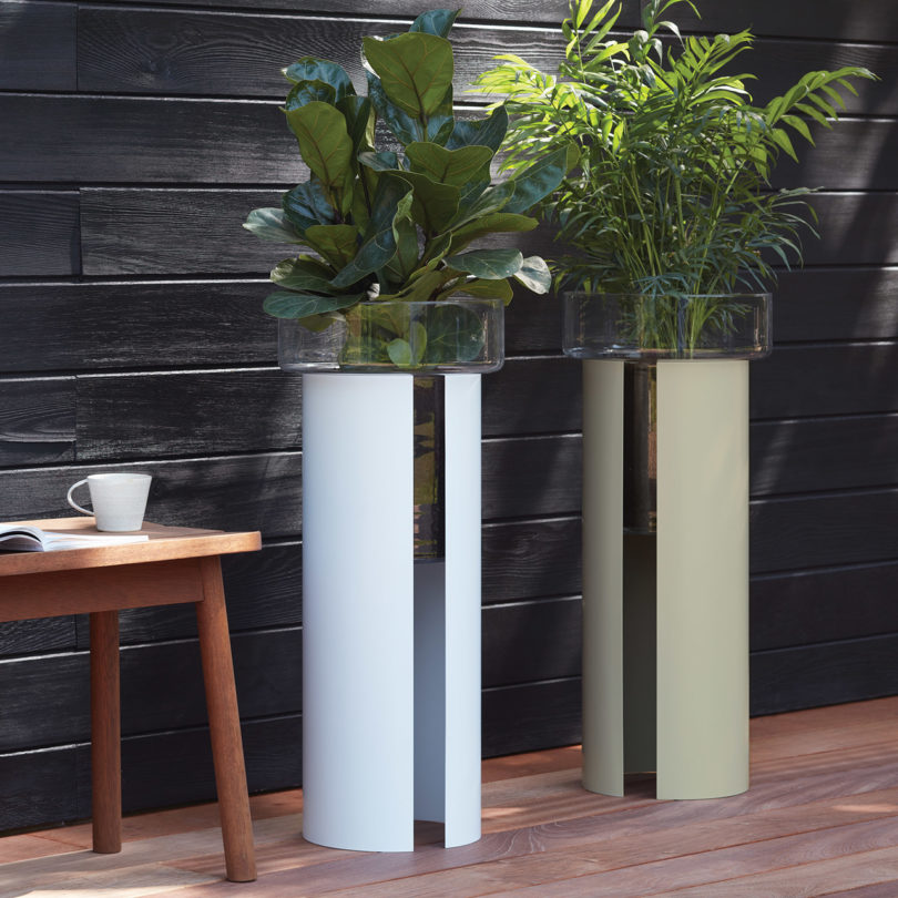 two self-watering glass planters on the floor outdoors