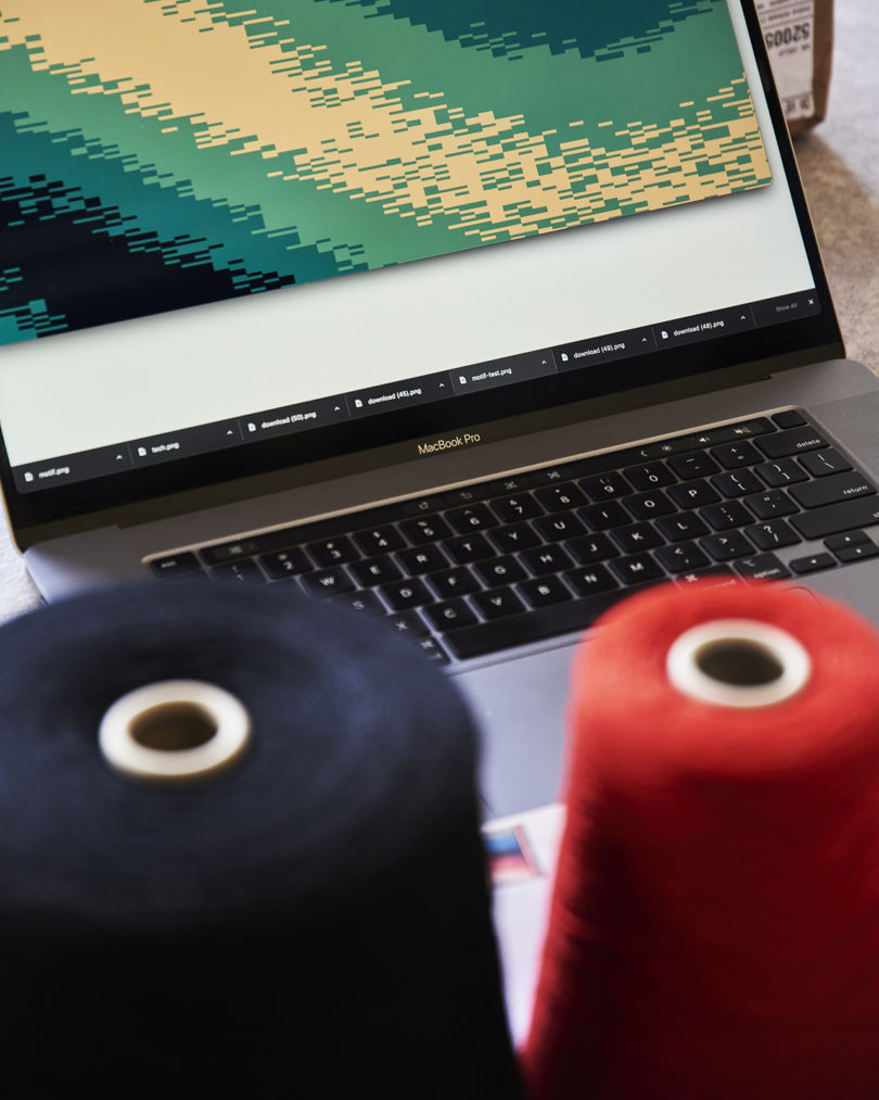 a laptop with a predominantly blue design on it with two spools of thread sitting in the foreground